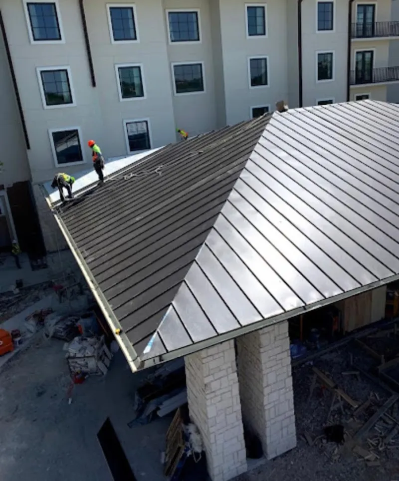Crew installing standing seam metal roof panels on a commercial project in Piqua